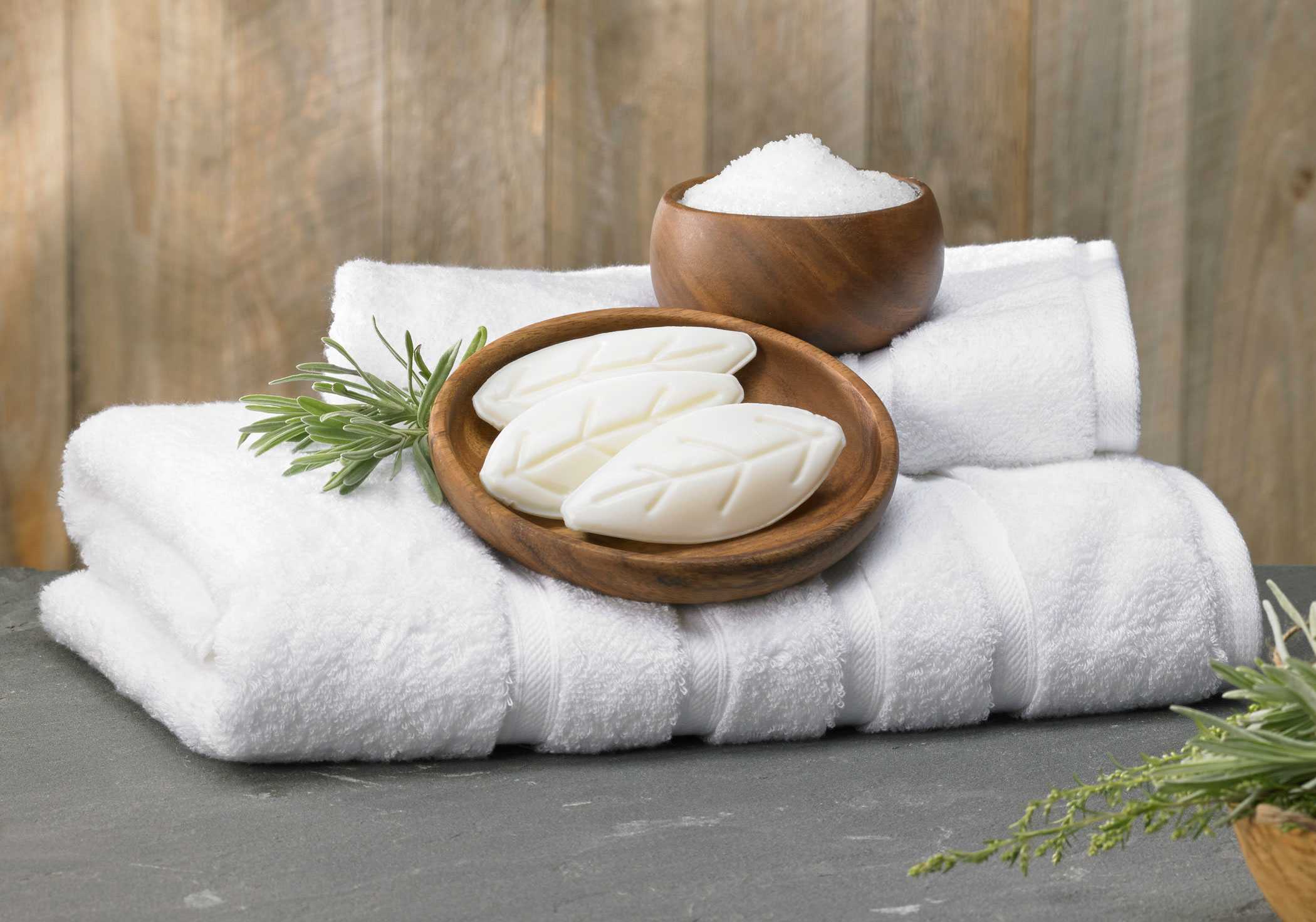 bars of soap held in wooden bowls on top of fresh towels