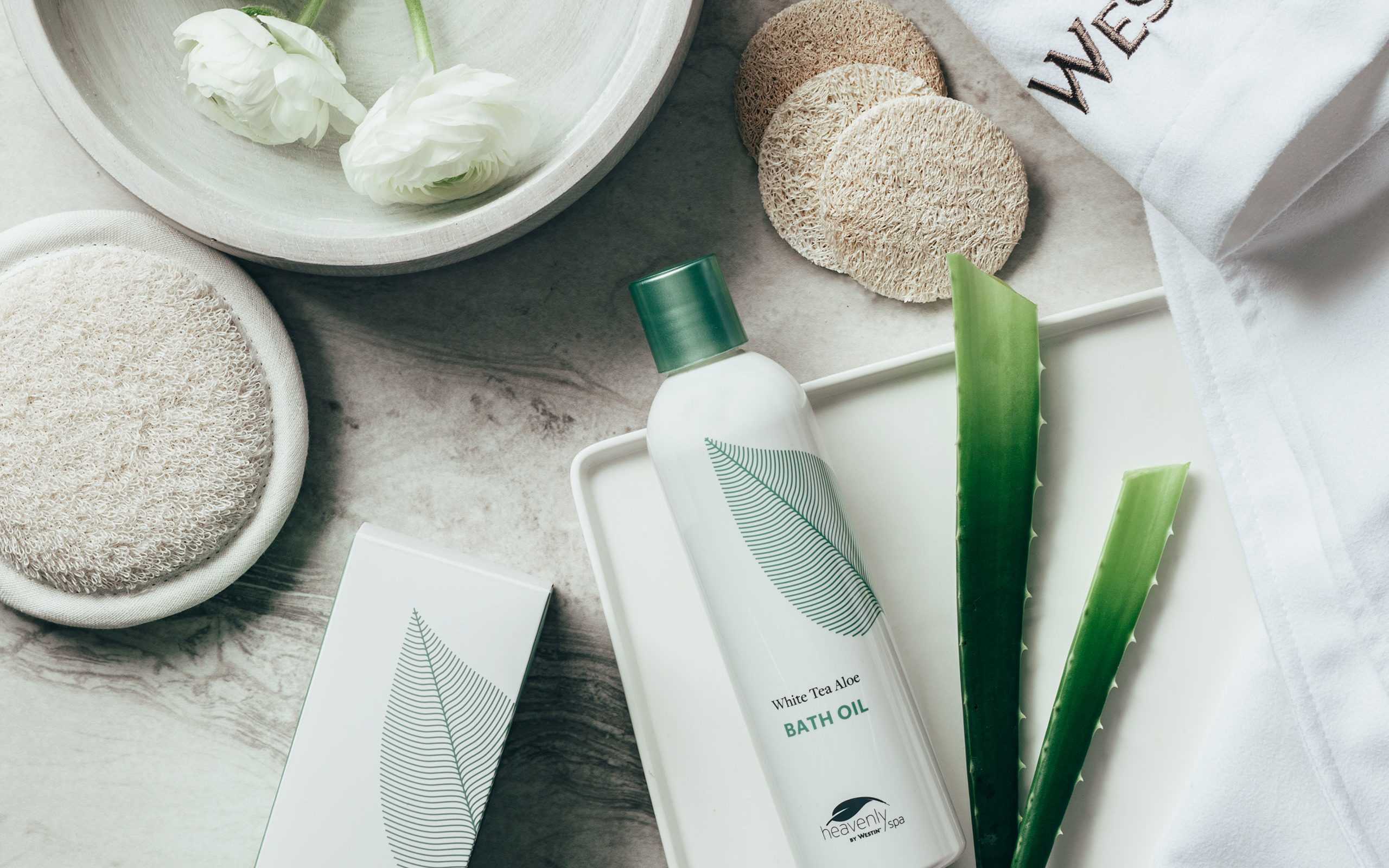 an array of fresh aloe massage creams and flowers next to a robe