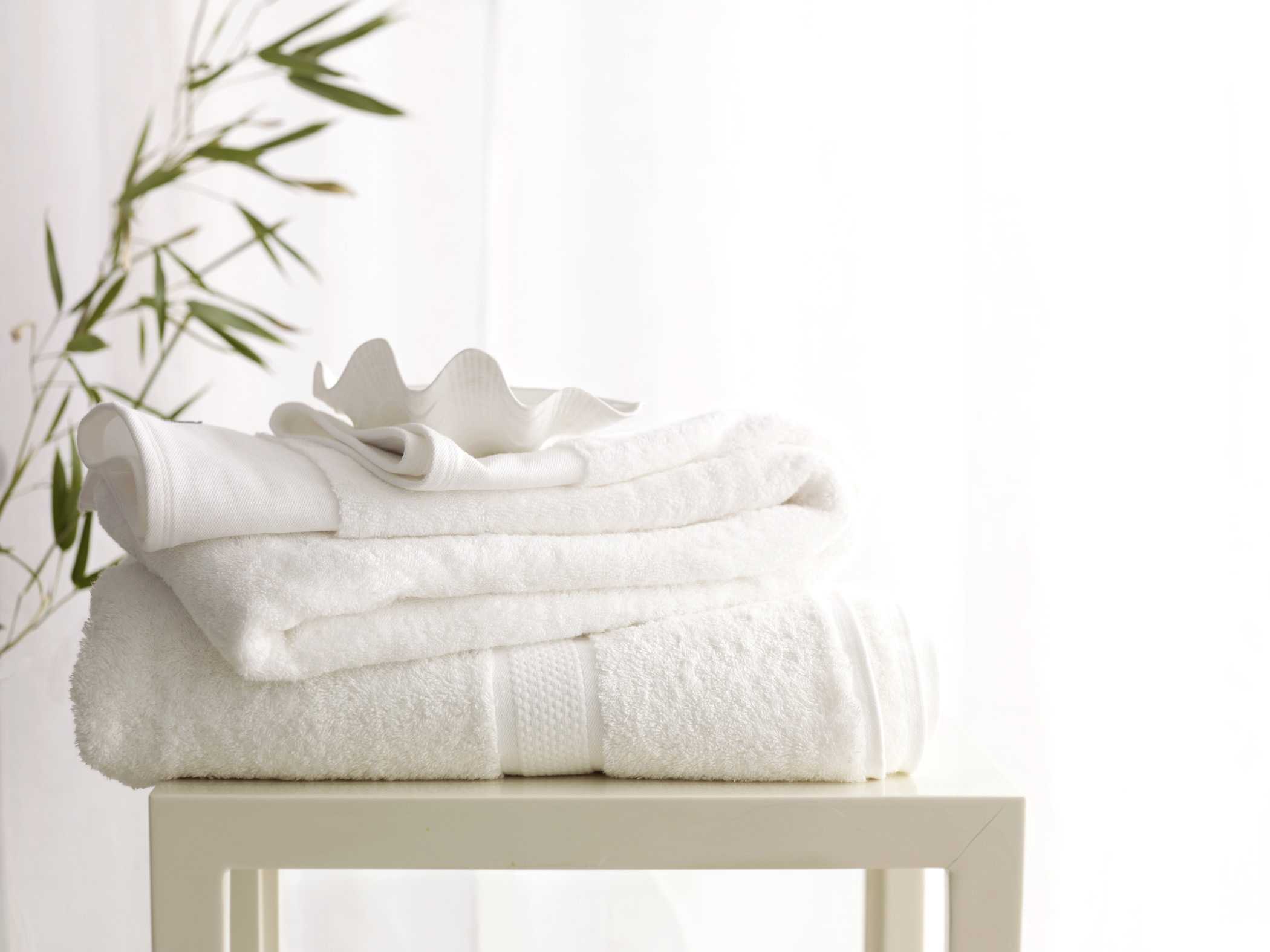 fresh white towels on top of a table next to plants