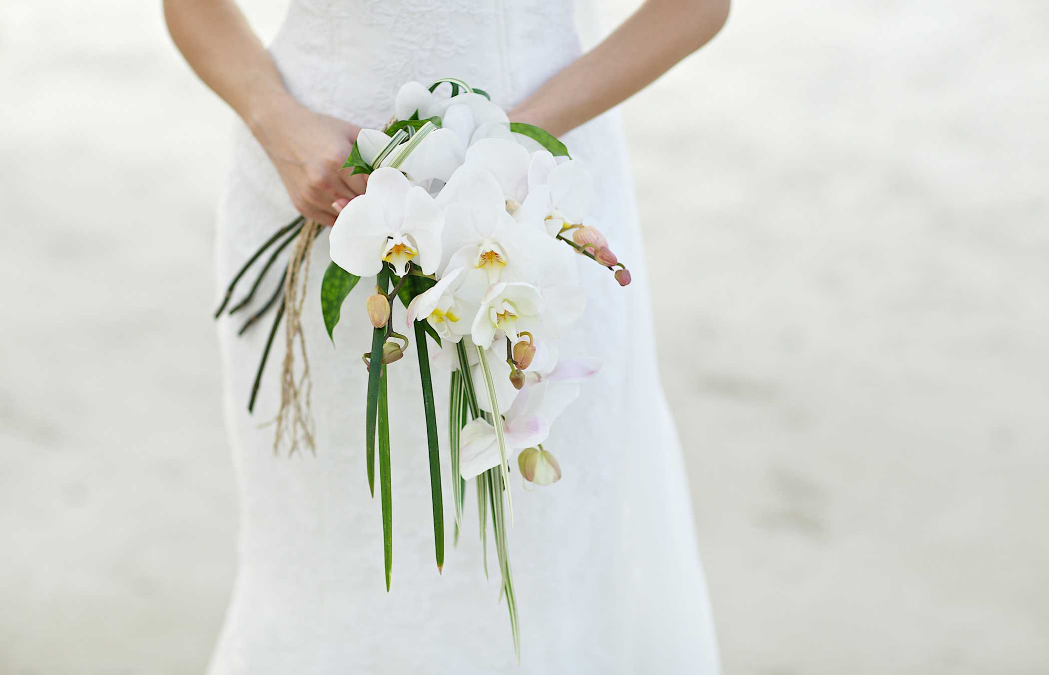 bride holding bouquet on sand